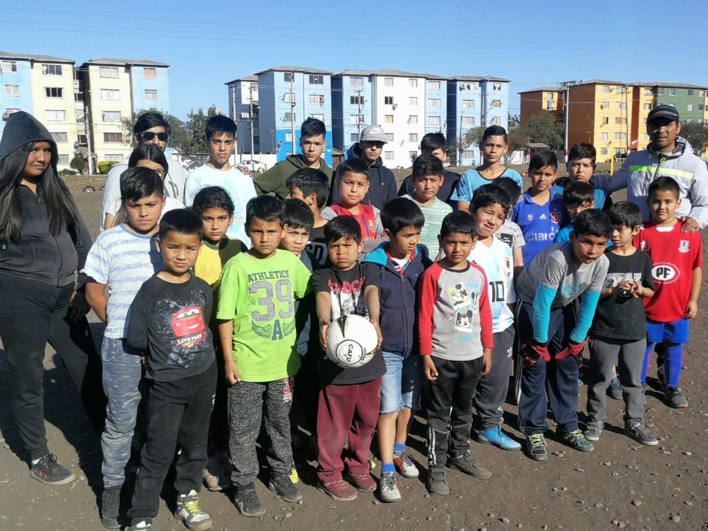 Jean Fuentes Astorga junto a niños y niñas de la Escuela de Fútbol Juventud Artificio.